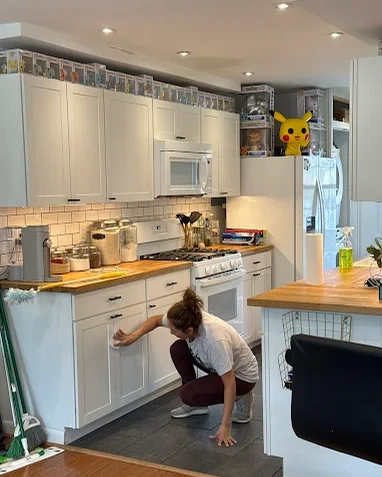 Owner of Fairfax Perfect Maids hand-wiping kitchen cabinet fronts